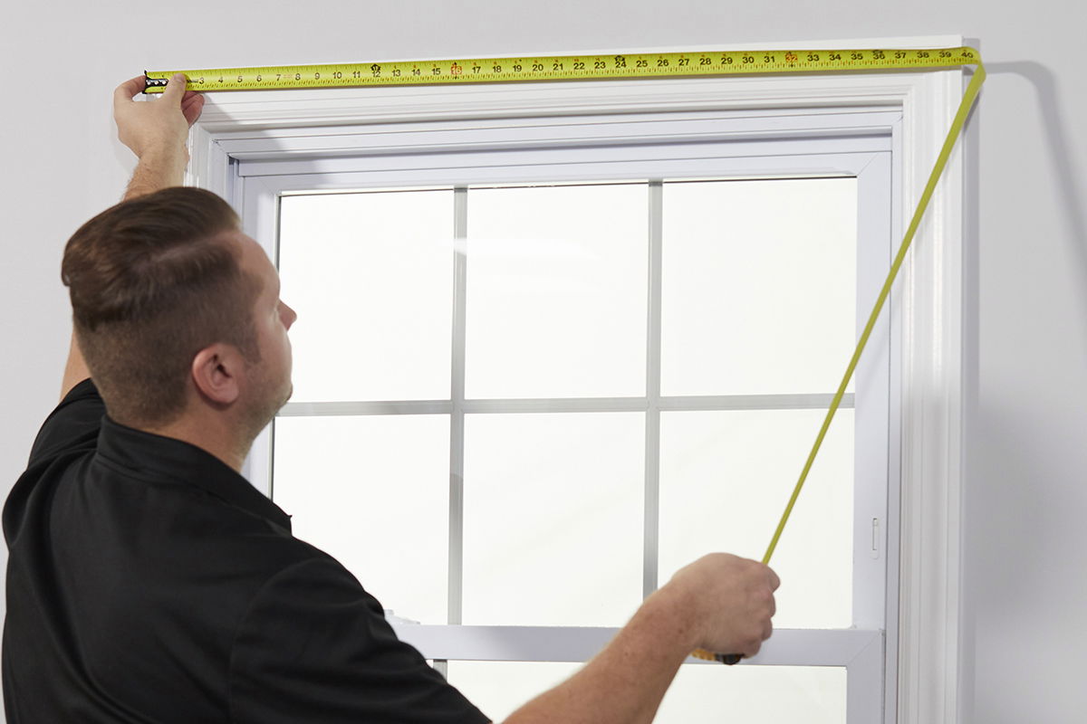 A measure technician measures a window frame.