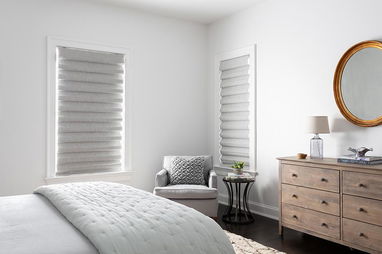 Classic fold roman shades in light grey cover two windows in a modern bedroom