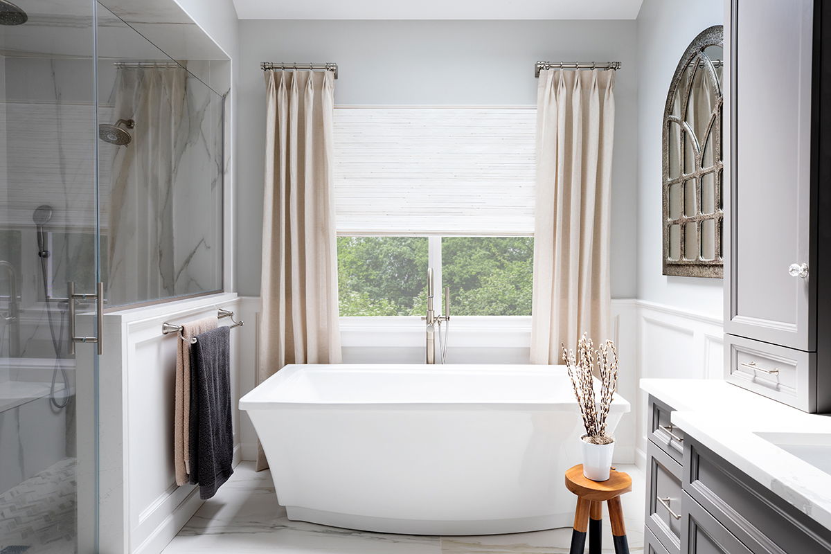 Drapery paired with woven wood shades in a modern bathroom.