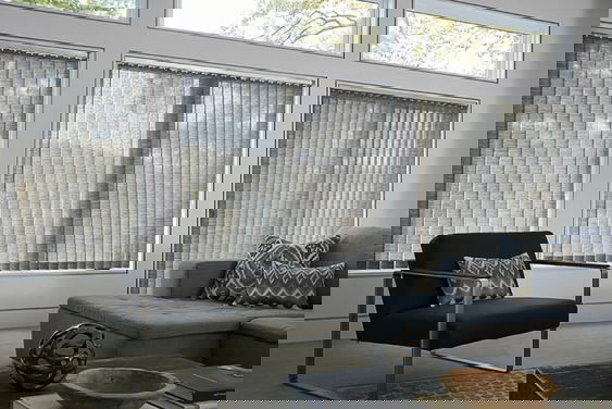 Vertical blinds made of custom fabric for sliding glass doors provide privacy and a modern living room .