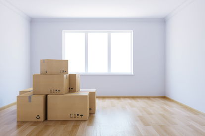 An empty room with moving boxes features a window with no window covering An empty room with moving boxes features a window with no window covering