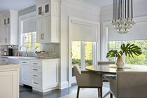 Dining area with white roller shades on windows