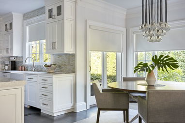 Dining area with white roller shades on windows