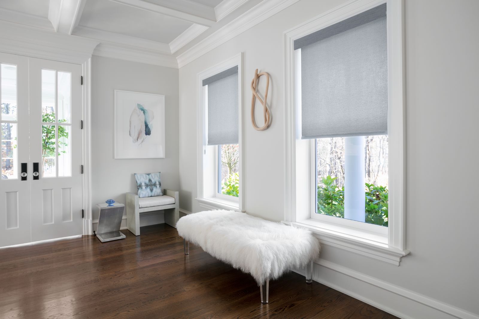 Grey inside mount roller shades cover two large windows in a modern living room.