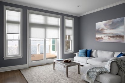 Roller shades cover a sliding glass door and windows on the left and right in a modern waterfront living room. Roller shades cover a sliding glass door and windows on the left and right in a modern waterfront living room.