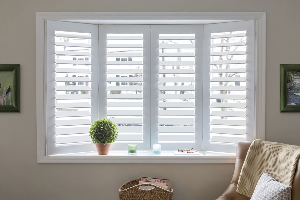 White shutters cover a bay window in a cozy living room.