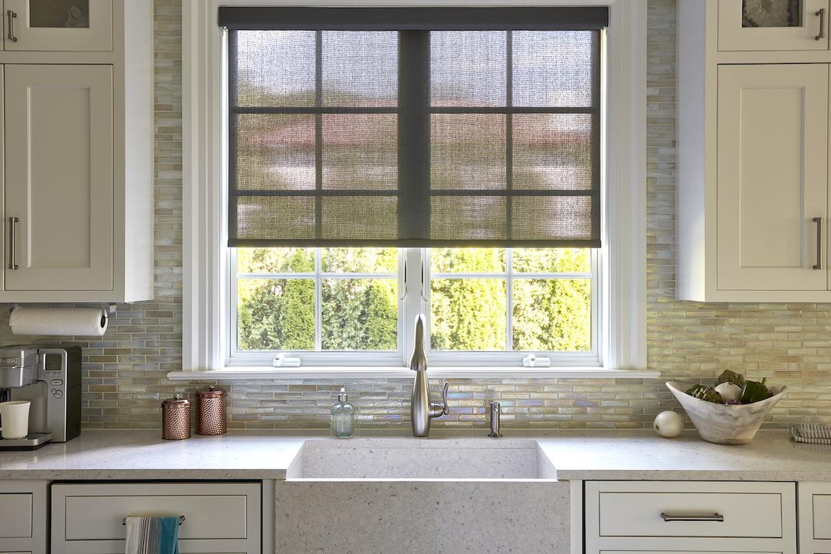 Solar shades cover a large window behind the sink in a modern farmhouse kitchen.