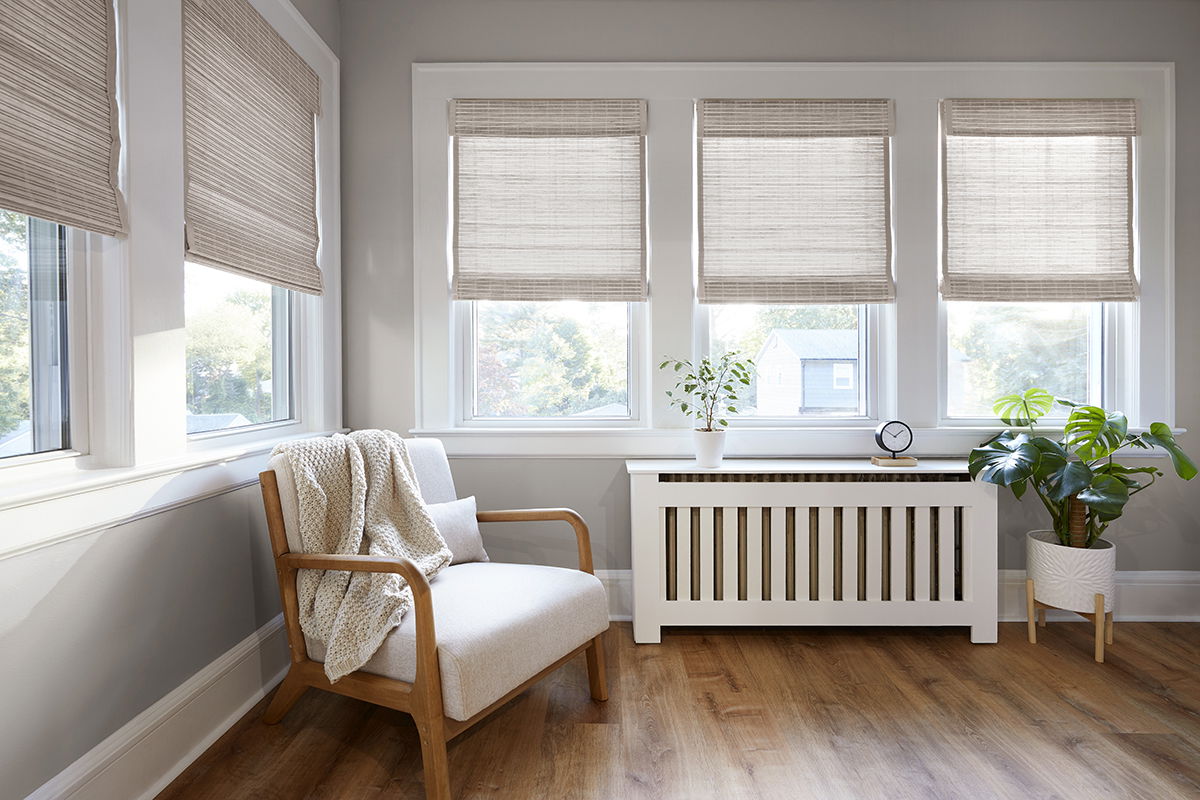 Woven wood shades cover five windows in a bright and modern sitting area.